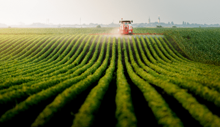 Agricultural field with a tractor processing crops, representing organic waste processing and various agricultural applications