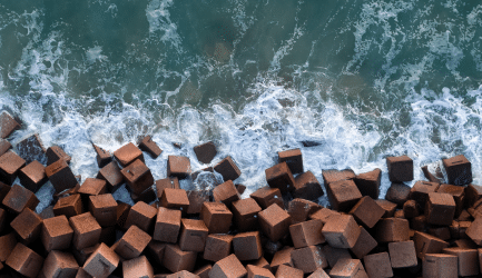 Coastal resilience structures with waves crashing against concrete blocks, symbolizing waste management and environmental fortification